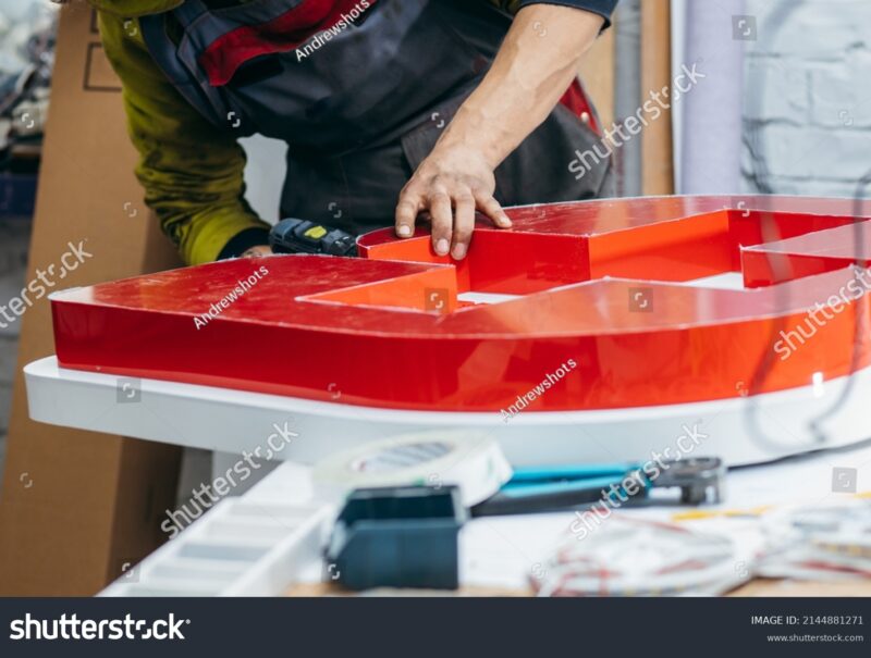 stock-photo-young-worker-with-a-drill-in-his-hand-collects-an-advertising-sign-2144881271 (1)